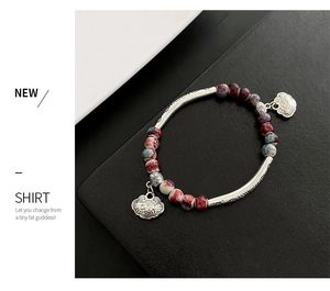 Macro detail of handmade ceramic bracelet with blue red beads and silver Ruyi lock charms
