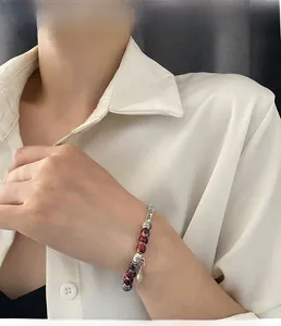 Detail of vintage ceramic beaded bracelet with silver fish charm on model wrist
