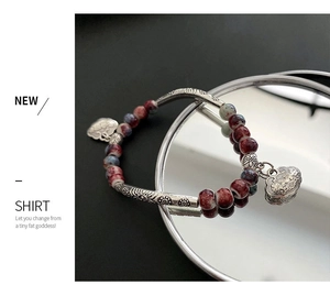 Detailed close-up of a vintage ceramic beaded bracelet with a silver Ruyi lock charm