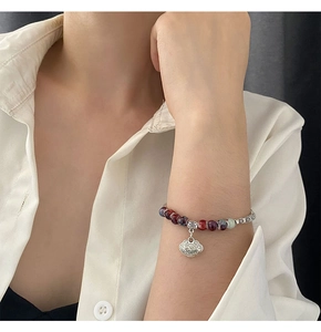 Close-up of handmade ceramic beaded bracelet with a silver longevity lock pendant