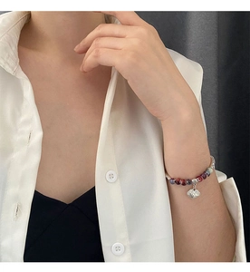 Detail of colorful ceramic beaded bracelet with silver lock charm on female wrist