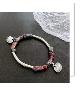 Ethnic ceramic bracelet detail featuring kiln-fired beads and silver lock charms