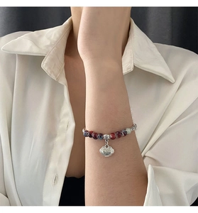 Macro view of ceramic bead bracelet with silver Auspicious Cloud Ruyi lock pendant