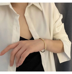 Détail d'un bracelet doré à fermoir lettre avec oxyde de zirconium sur poignet