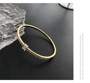 Gros plan d'un bracelet doré orné d'un zircon carré et de détails en pavé de diamants
