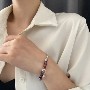 Ethnic ceramic beaded bracelet with silver fish charm worn on woman wrist