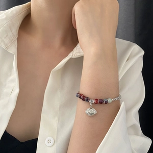 Ethnic style ceramic beaded bracelet featuring a vintage silver Ruyi lock charm on wrist