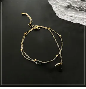 Macro shot of gold double-layer anklet featuring traditional coin charms on black background
