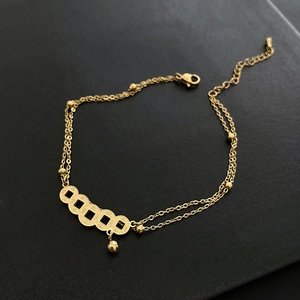 Vintage gold layered anklet with ancient coin charms and small beads on black background