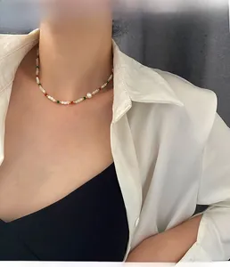 Detail of colorful beads and freshwater pearl necklace worn over white shirt and vest