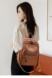 Detail of brown leather backpack featuring kangaroo metal logo and woven side straps