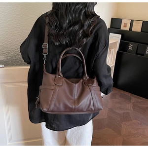 Detail of vintage dark brown tote bag with pebble leather texture and adjustable shoulder strap