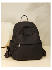 Close-up of textured dark brown backpack with multiple utility pockets and metal logo
