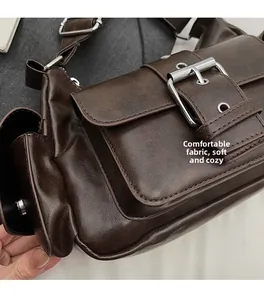 Detail of soft brown retro faux leather texture and metallic buckle on crossbody bag