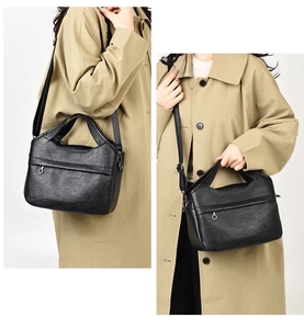 Detail of vintage black textured handbag with circular zipper pull and crossbody strap