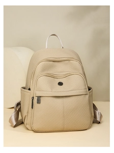 Close-up of beige canvas backpack showing textured fabric and front zipper pocket detail