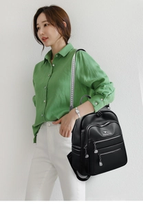 Detail of black leather backpack featuring kangaroo logo and metallic zipper pocket