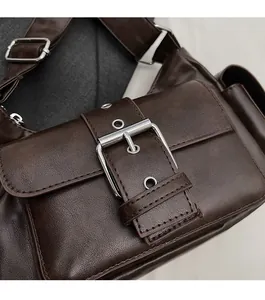 Close-up of retro brown leather shoulder bag featuring glossy finish and silver buckles