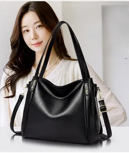 Close-up of black litchi grain leather texture and golden rivet details on bucket bag