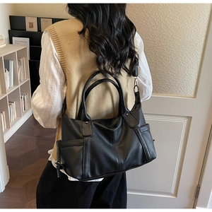 Rear view of a black pebble leather tote bag shown on a model for size and fit