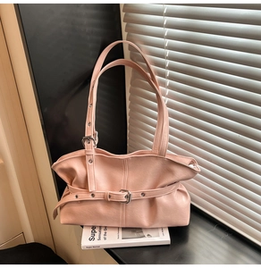 Détail du sac à bandoulière rose plissé en cuir PU avec boucle sur une surface noire