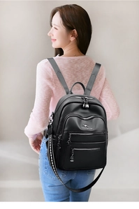 Detail of black pebbled leather backpack with multiple zip pockets and kangaroo logo