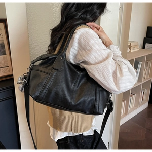 Detail of black pebbled leather tote bag showing large capacity and adjustable strap