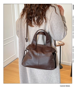 Rear view of model holding a brown litchi pattern leather tote bag with shoulder strap