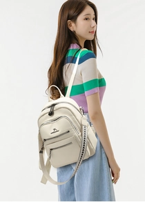 Close-up of cream faux leather backpack with litchi texture and metal kangaroo logo detail
