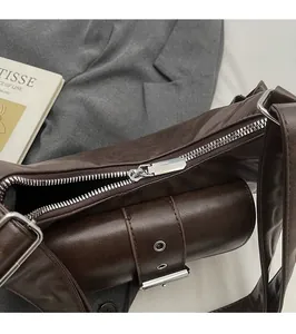 Detail of smooth silver zipper and side buckle pocket on textured brown leather bag