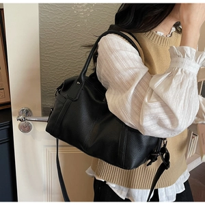 Detailed view of black pebbled leather texture and metal strap hook on retro tote bag