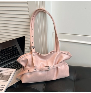 Détail du sac à bandoulière plissé rose clair avec boucle métallique sur siège en cuir