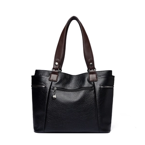 Sac cabas en cuir noir avec anses marrons et texture grainée sur un fond blanc pur