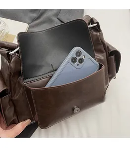 Close-up of retro brown faux leather shoulder bag featuring a functional front phone pocket