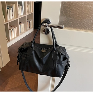 Detail of vintage black pebble leather tote bag hanging on a white door handle