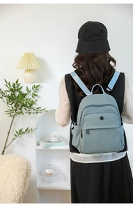 Detail view of grey-blue nylon backpack texture with multiple compartments on a model