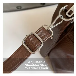 Detail of adjustable leather shoulder strap with silver metal buckle on brown tote bag