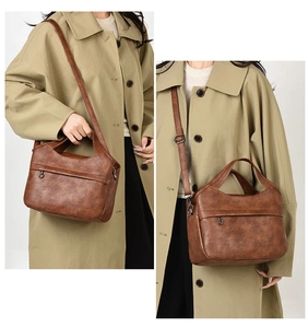 Detail of vintage brown tote bag featuring zippered front pocket and adjustable shoulder strap