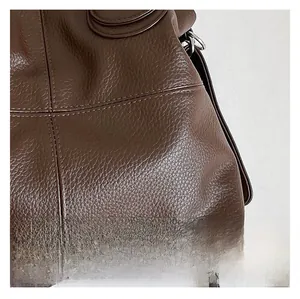 Close-up of deep brown lychee grain leather texture with refined double stitching details