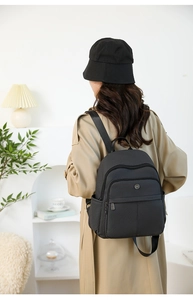Side view of woman wearing minimalist black travel backpack with side pocket details
