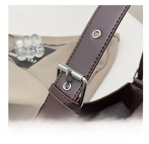 Detail view of adjustable dark brown leather shoulder strap with silver metal buckle and eyelets