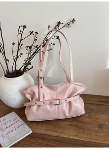 Détail du sac à main en cuir plissé rose pâle avec boucles argentées sur bois