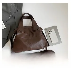 Top view of brown lychee grain handbag next to a blazer and phone for scale reference