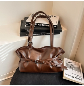 Détail du sac à épaule en cuir marron foncé avec plis et boucle en métal argenté