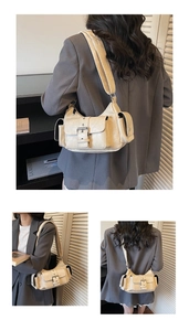 Detail view of the multi-pocket cream shoulder bag with silver buckle and side pocket