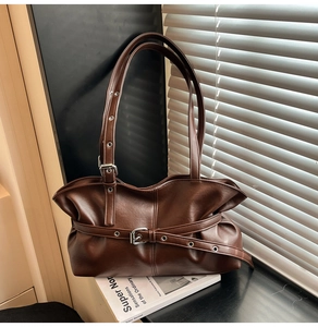 Détail du sac bandoulière vintage marron foncé avec boucles argentées et cuir plissé