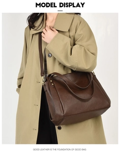 Detail of dark brown pebble leather tote bag with sturdy handles and gold hardware
