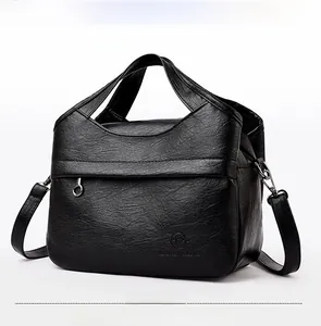 Detail of black pebbled leather handbag featuring sturdy dual handles and adjustable strap