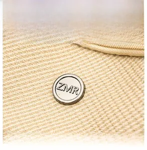 Close-up of beige woven backpack texture with silver ZMR metal logo and smooth zipper