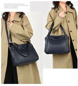 Detail showing the navy blue pebble leather tote and adjustable crossbody strap with gold hardware